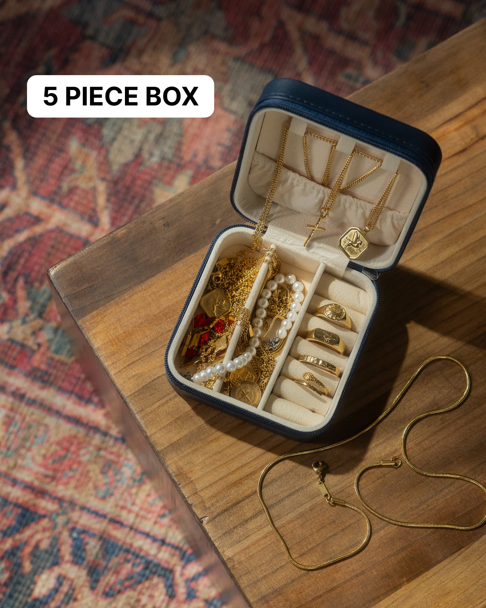 Open jewelry box filled with gold chains and pearl bracelets on a rug