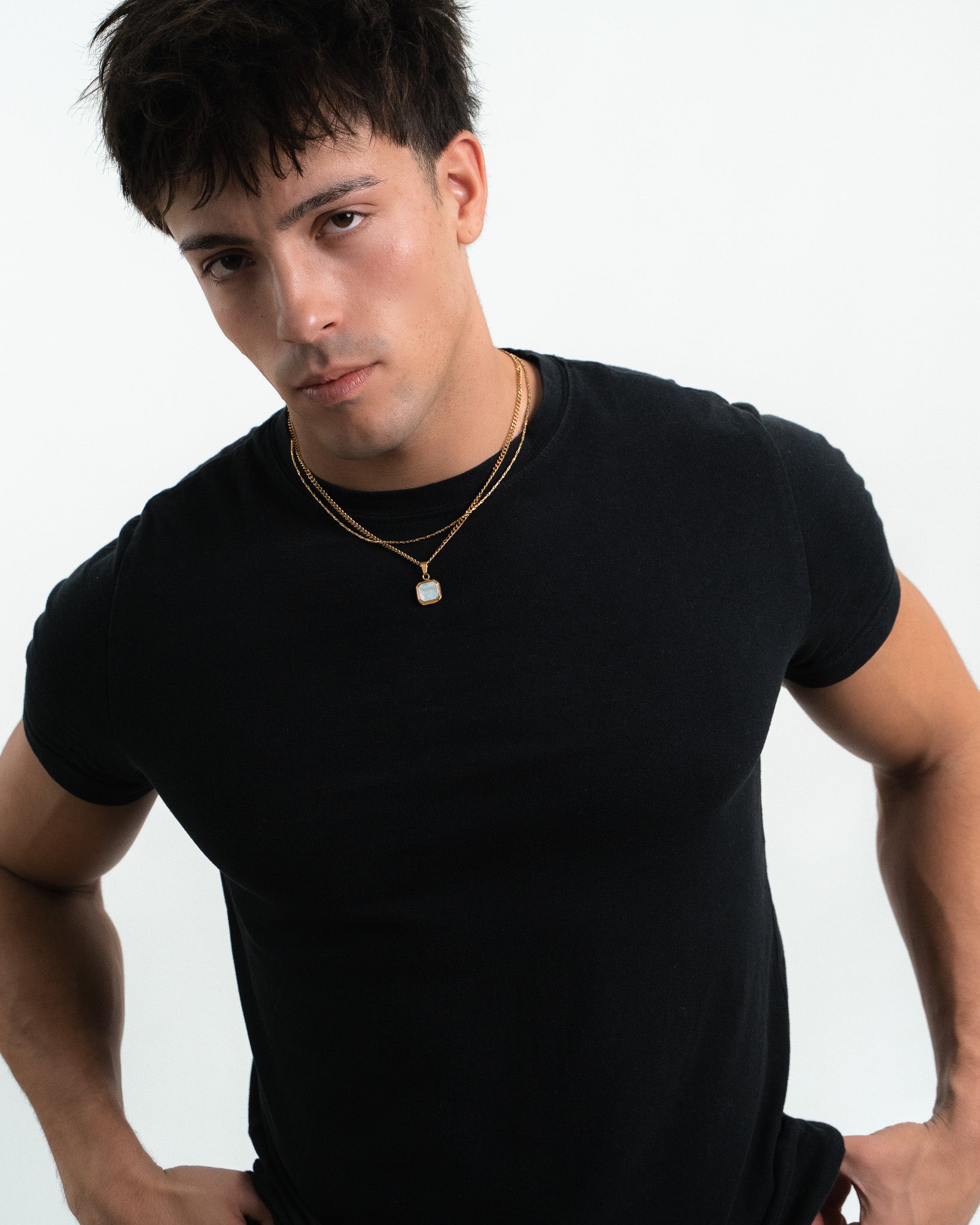 Close up of a model wearing a layered NOVA GOLD necklace with a square pendant