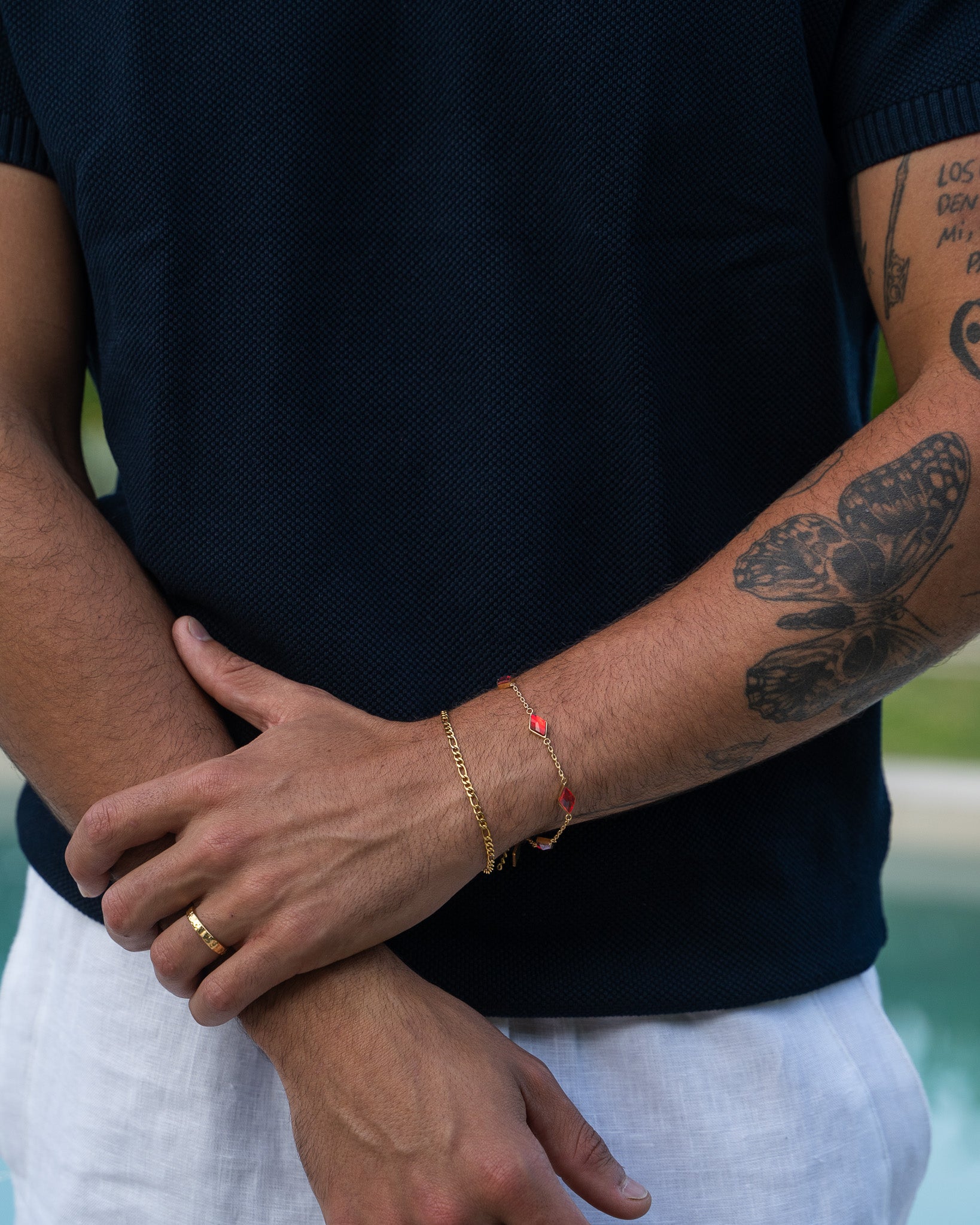 Hammered gold ring on a finger with dark skin against a navy knit shirt