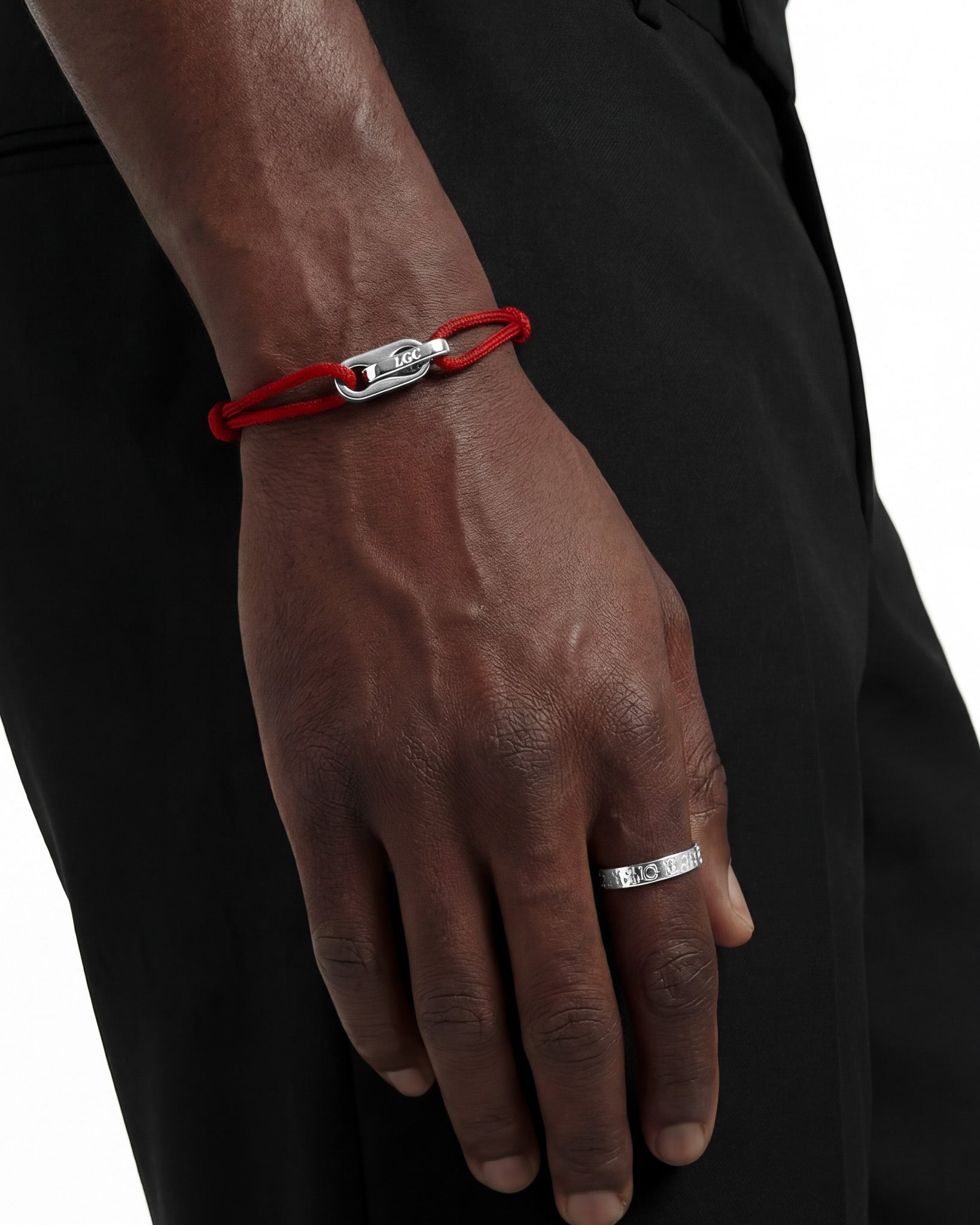 Close up of a red cord Atlantis bracelet on the wrist showing the engraved silver clasp