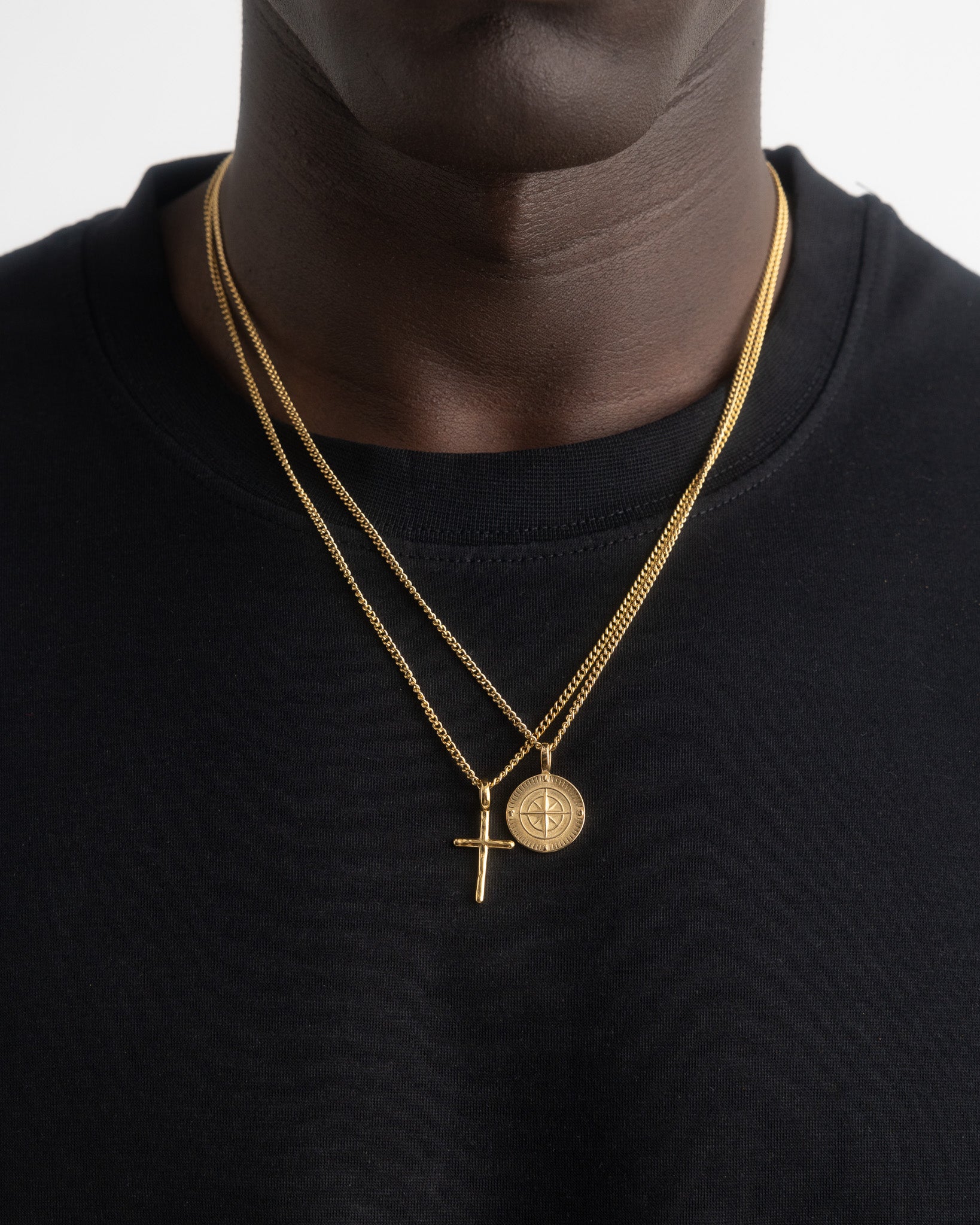 Back view of a person wearing two NORTHWALK gold necklaces with a compass pendant at the chest.