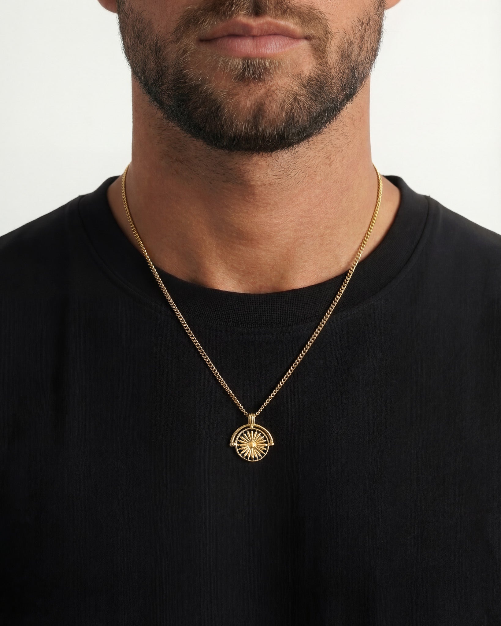 Daisy gold necklace with a round sunburst pendant resting on a black shirt