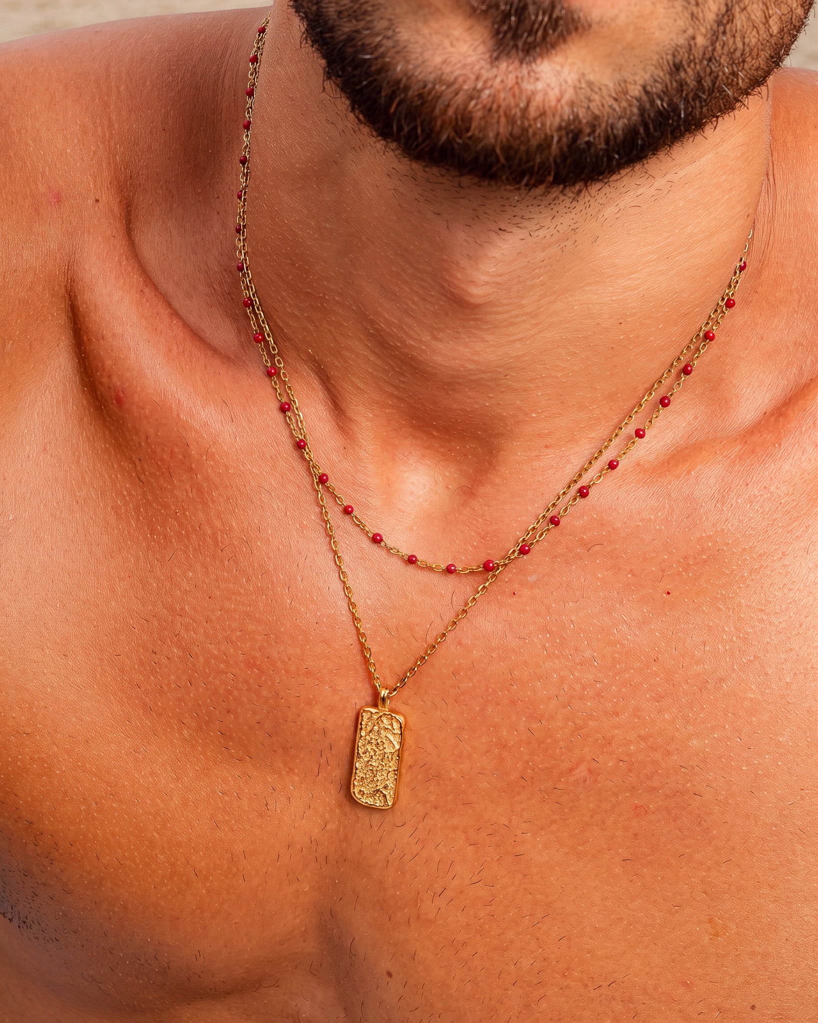 Man wearing a gold chain with red bead accents draped around his neck