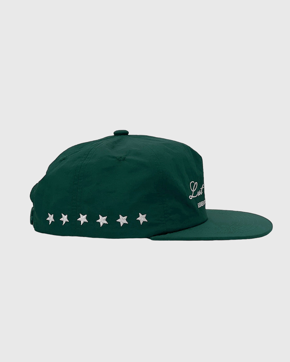 Vista en tres cuartos de gorra verde de nailon con logo bordado en el frontal y estrellas en la parte trasera.