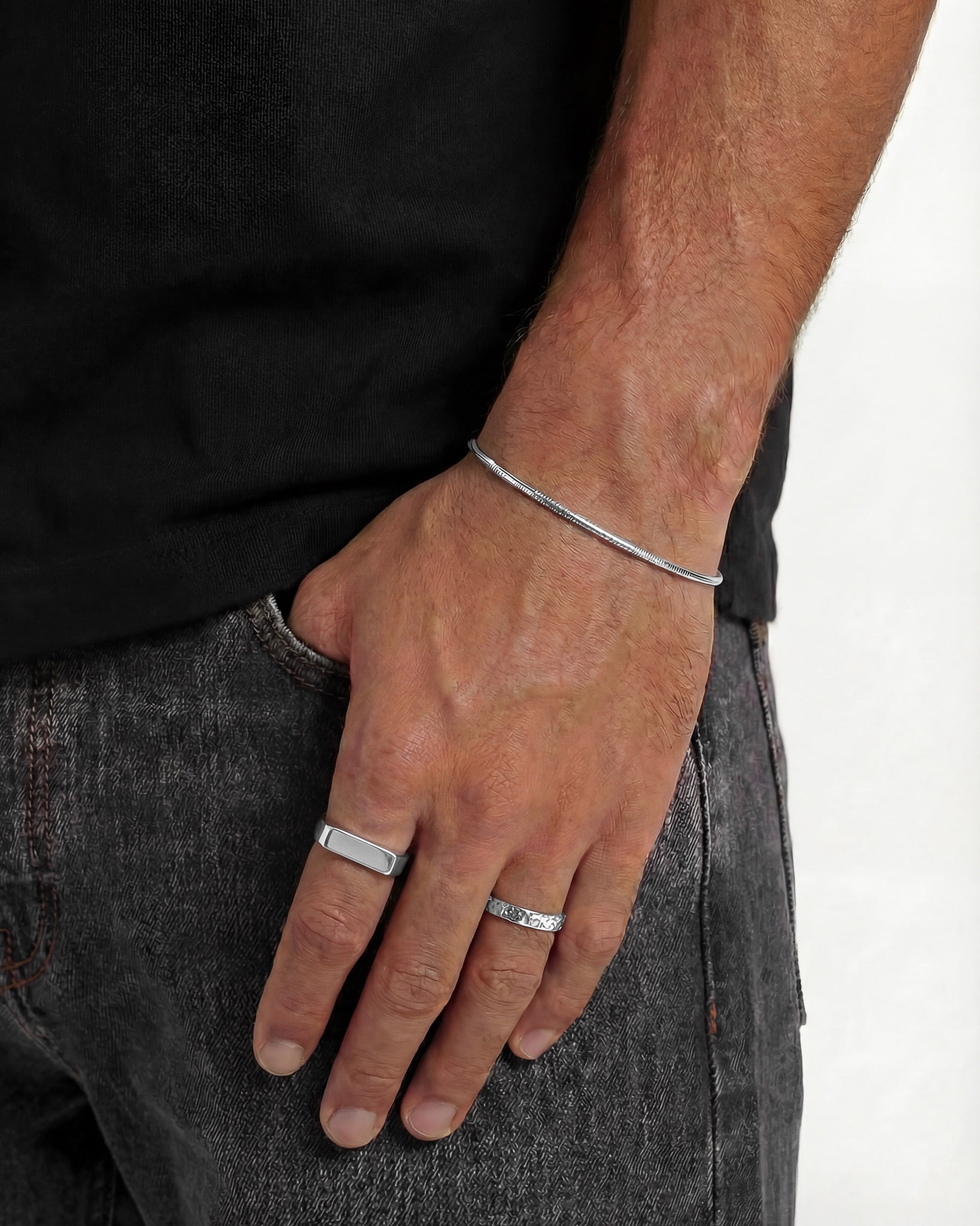 MILO silver rings on a man's hand featuring a slim textured band and a smooth curved band