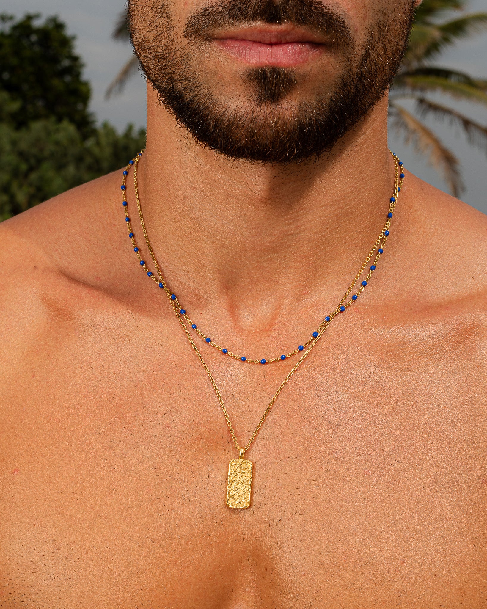 Moonrock gold necklace with blue beads worn by a man, close up of neck and beard