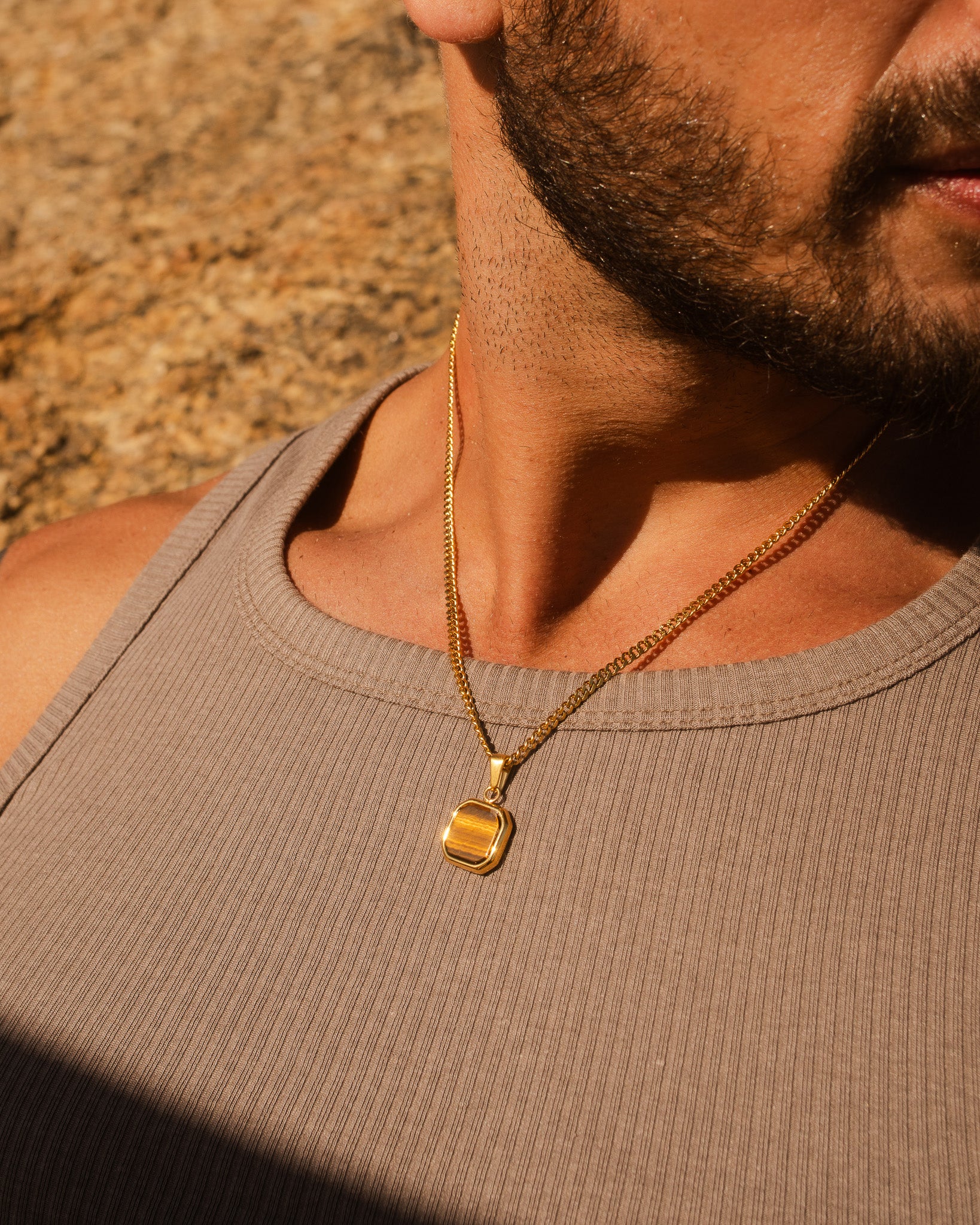 NOVA GOLD NECKLACE close up on a man's chest showing a gold chain and pendant.