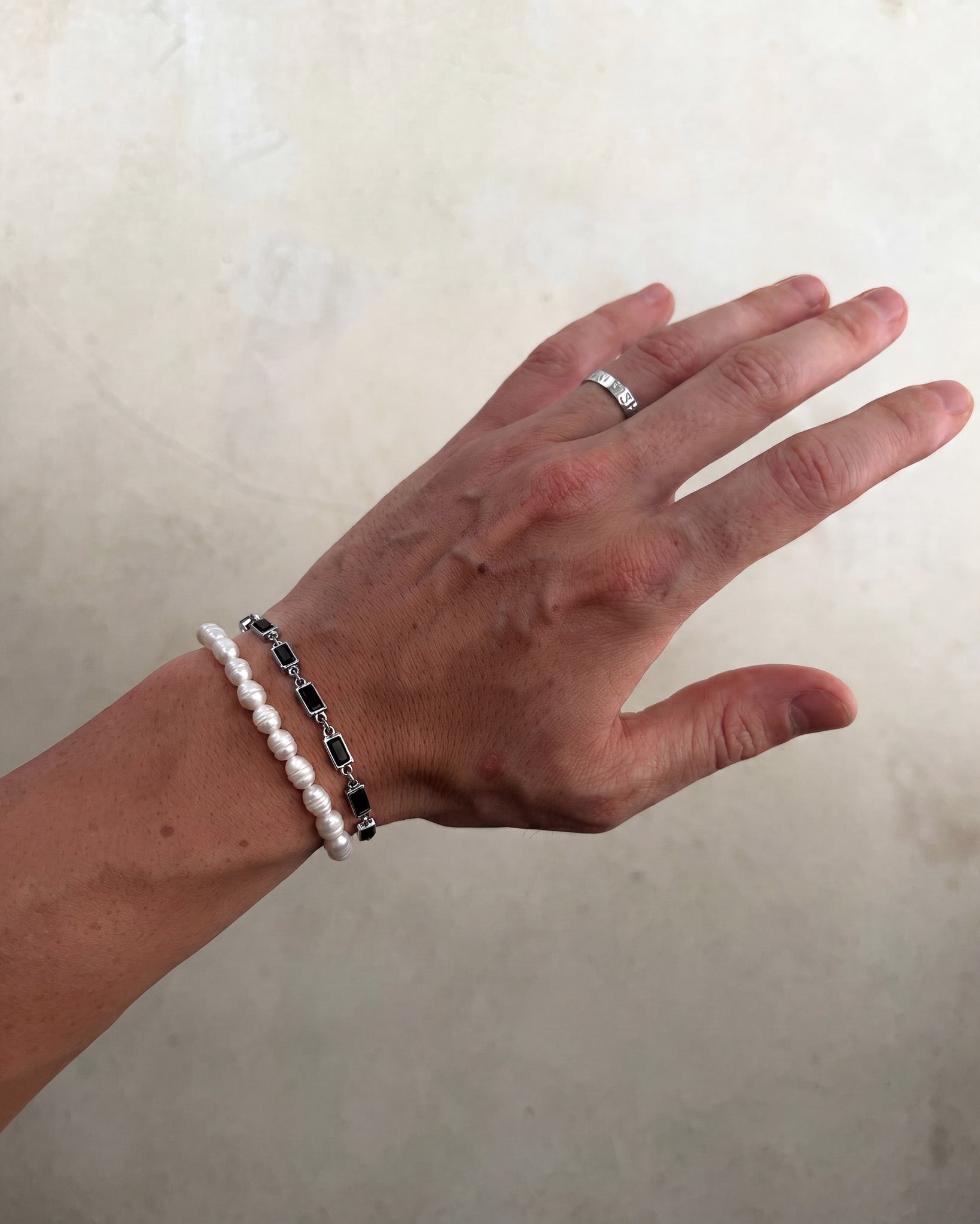 Pulsera plateada OMEN con eslabones de piedra cuadrada negra en la muñeca.