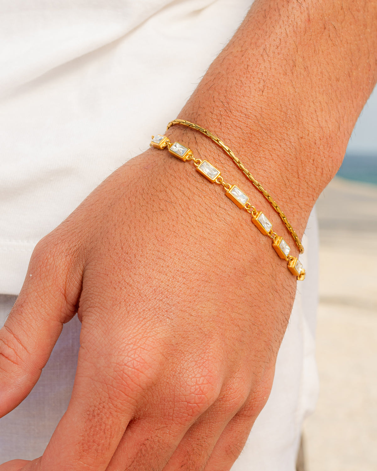 Pulsera OMEN GOLD, primer plano de las piedras rectangulares transparentes engastadas en eslabones de oro sobre cadena fina