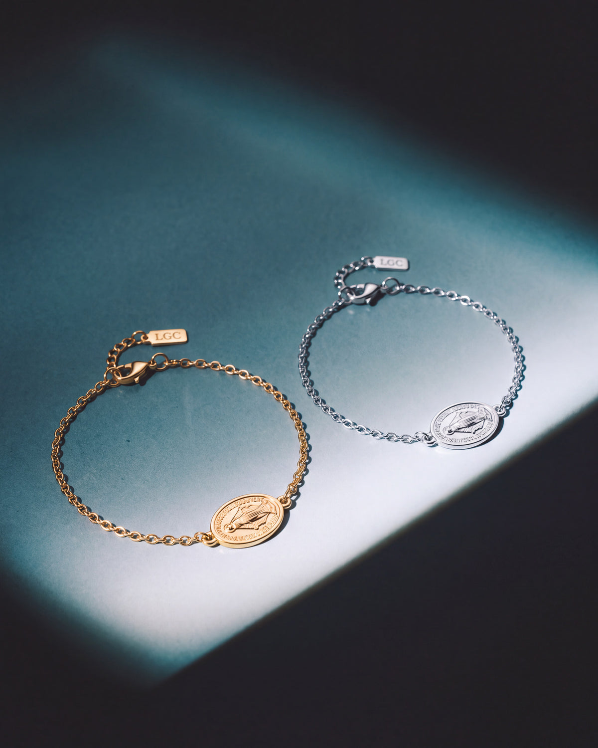Gold Virgin Mary bracelet with a medallion on a teal surface