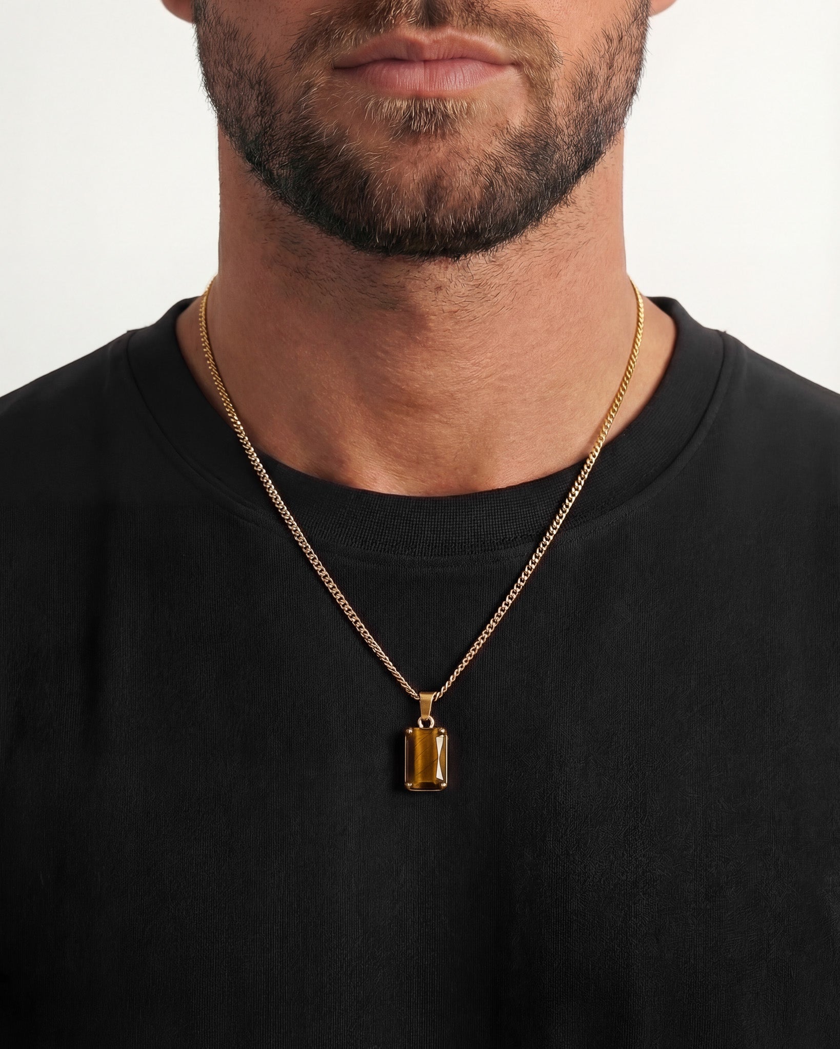 Gold VOLT necklace with rectangular tiger eye pendant worn over a black shirt