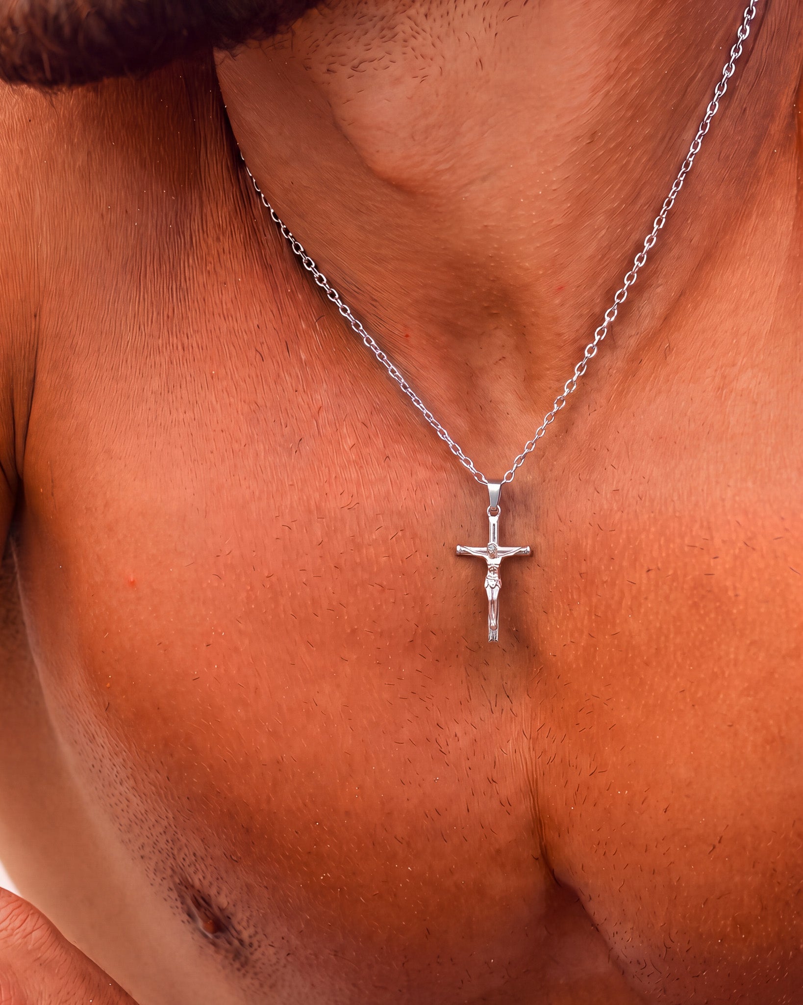 Collar de plata con crucifijo en el cuello, con el colgante a la altura de la clavícula