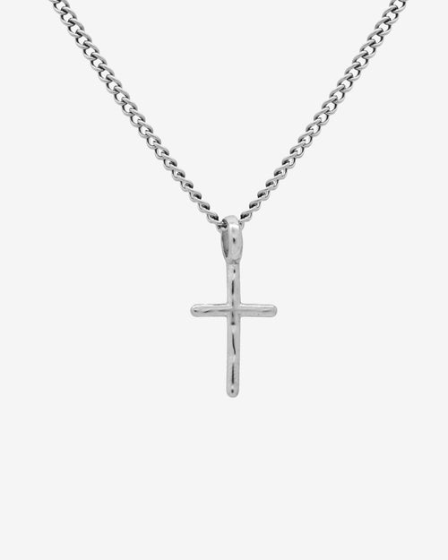 Silver cross pendant necklace on a chain resting against a white background