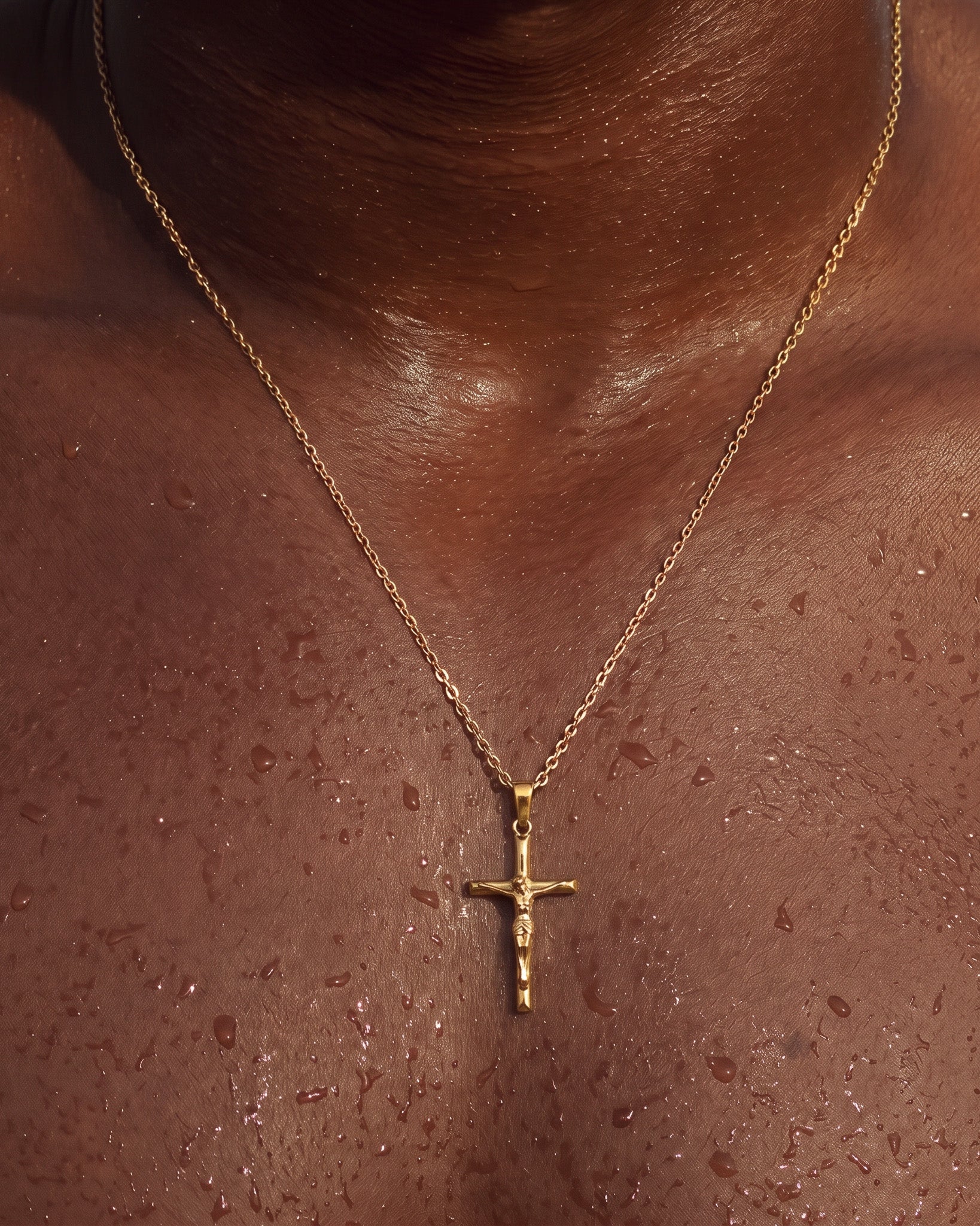 Collar de oro con crucifijo sobre el pecho, con el colgante a la vista