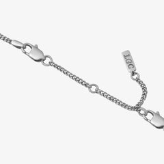 Close up of a silver 8 cm chain extender with a lobster clasp on a pale background