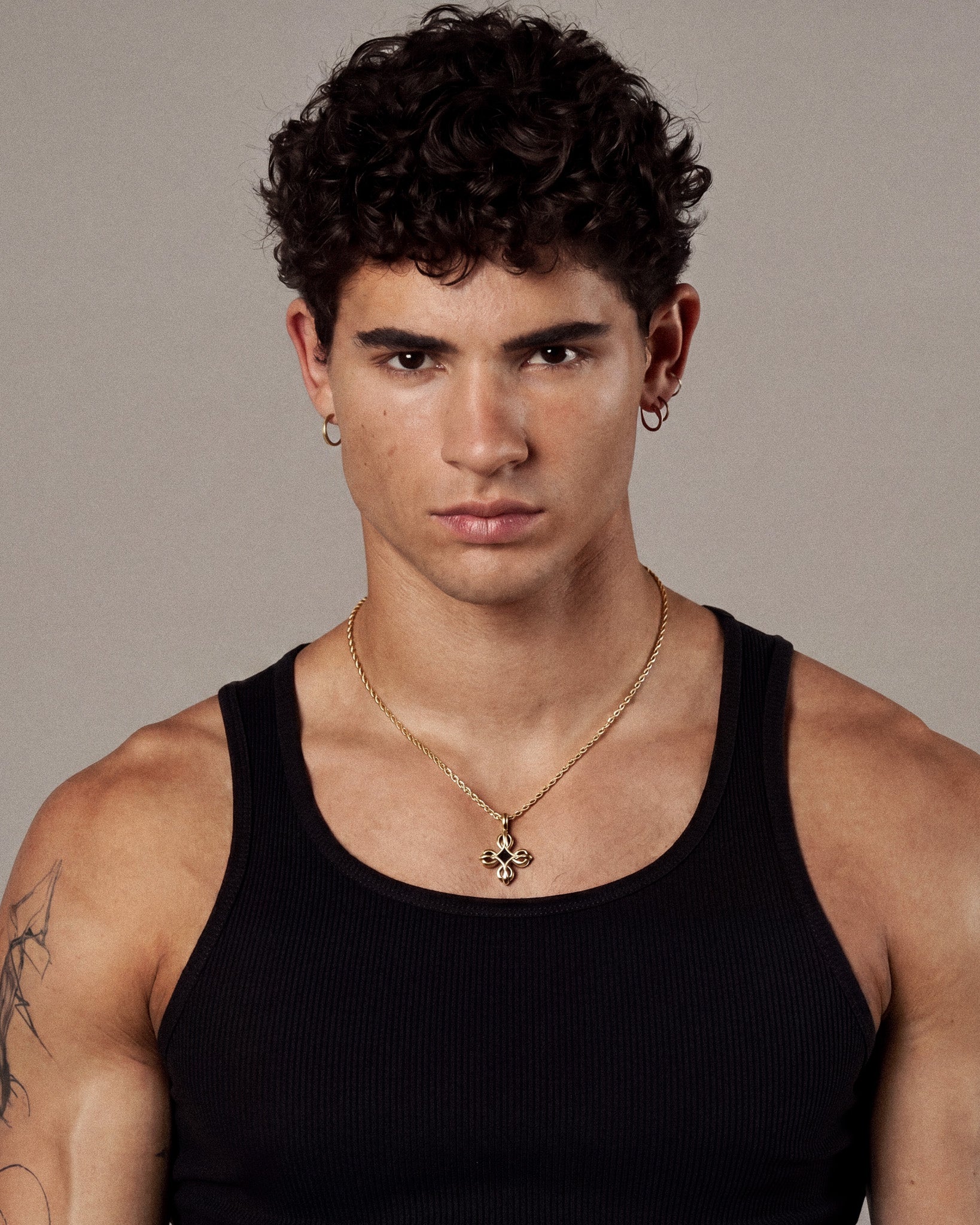 Portrait of a man wearing a gold chain necklace and hoop earrings