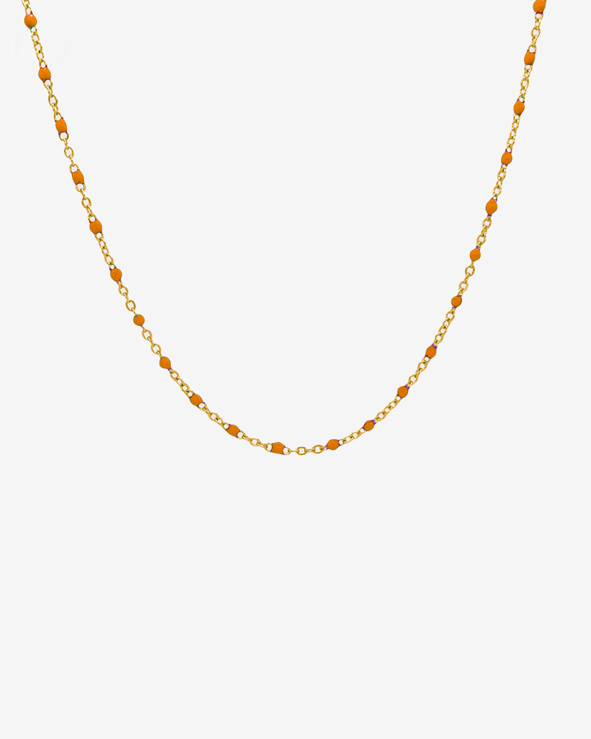 Collar de cadena dorada GEM con cuentas naranjas espaciadas en delicada cadena de eslabones dorados sobre fondo blanco