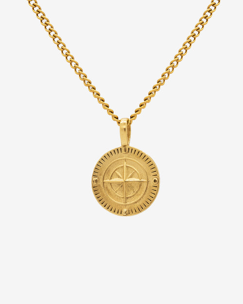 Gold chain necklace featuring a round compass pendant against a light background.