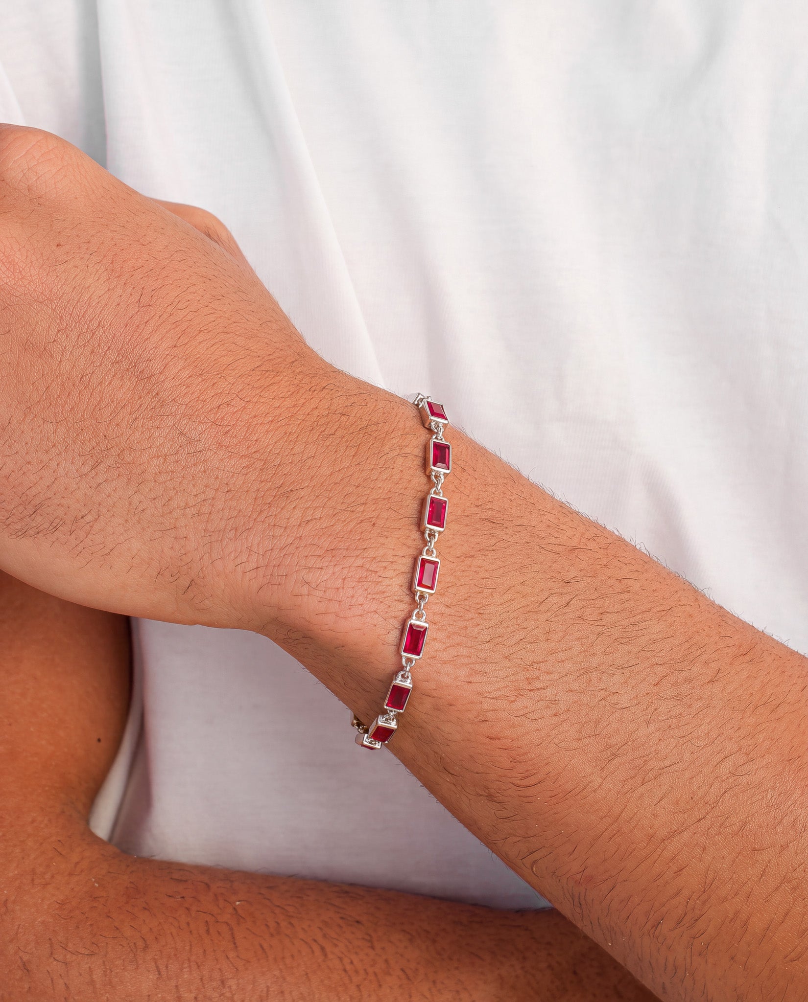 Pulsera OMEN de plata con piedras rectangulares rojas en la muñeca