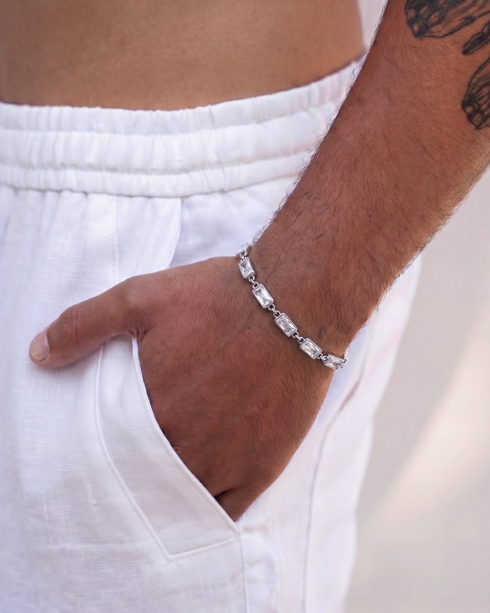 Silver OMEN bracelet with rectangular links on the wearer's wrist.
