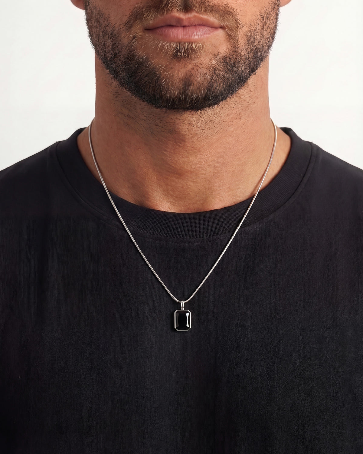 Solstice silver necklace with a small square pendant resting on a black t-shirt