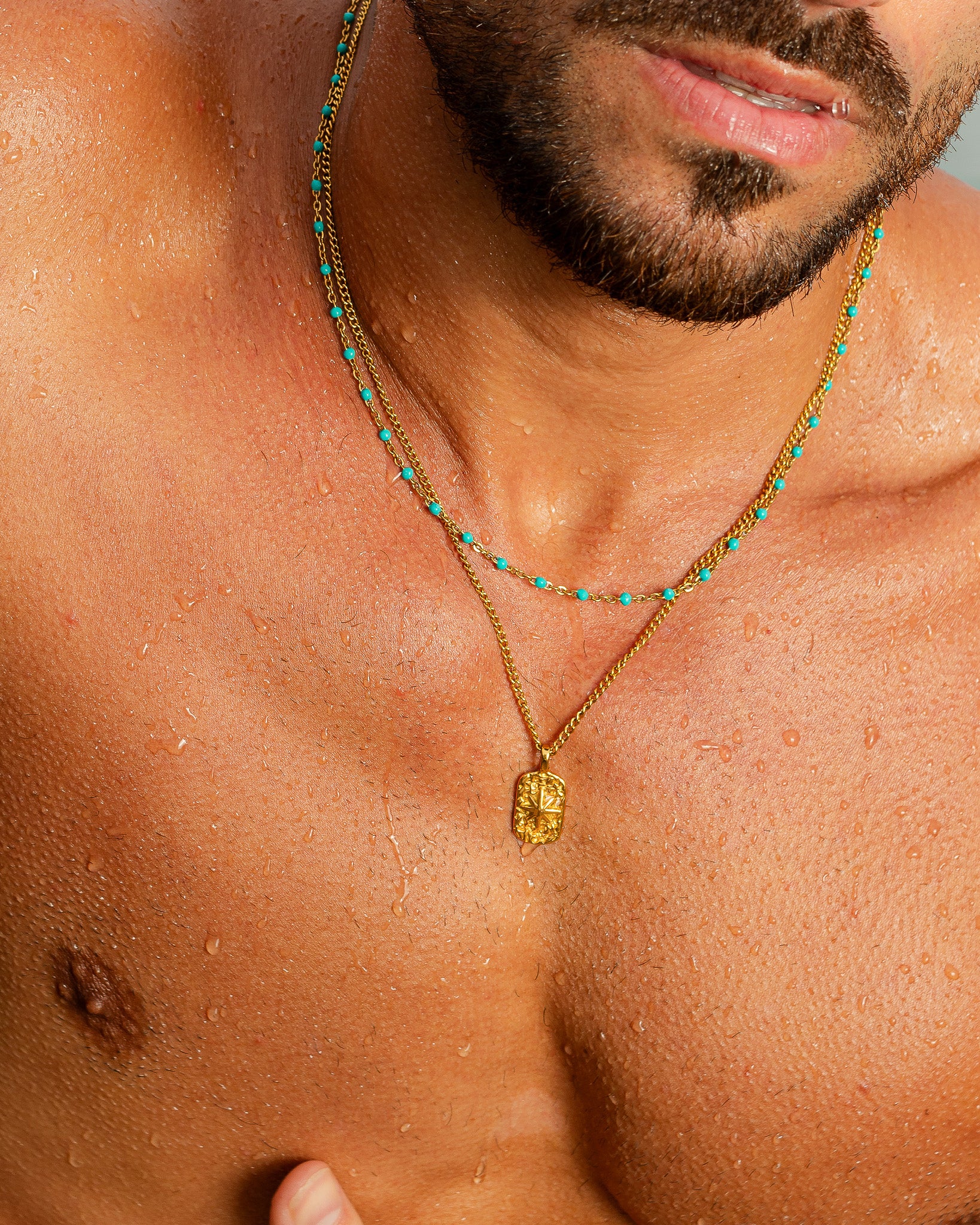 Gold chain necklace with turquoise beads draped on a man's neck