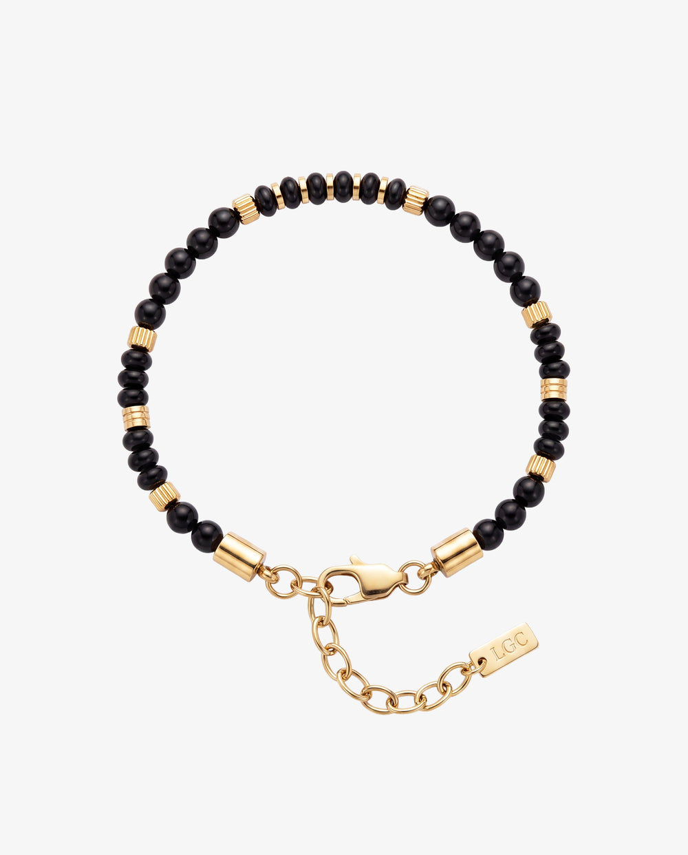 Pulsera de cuentas de ágata negra con separadores cilíndricos de oro en la muñeca