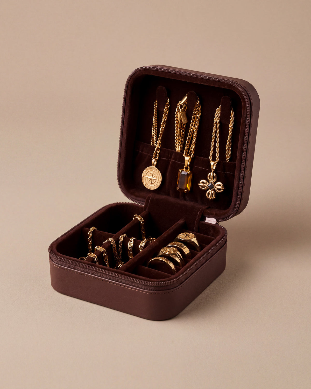 Open burgundy travel jewelry box displaying gold chains and pendants