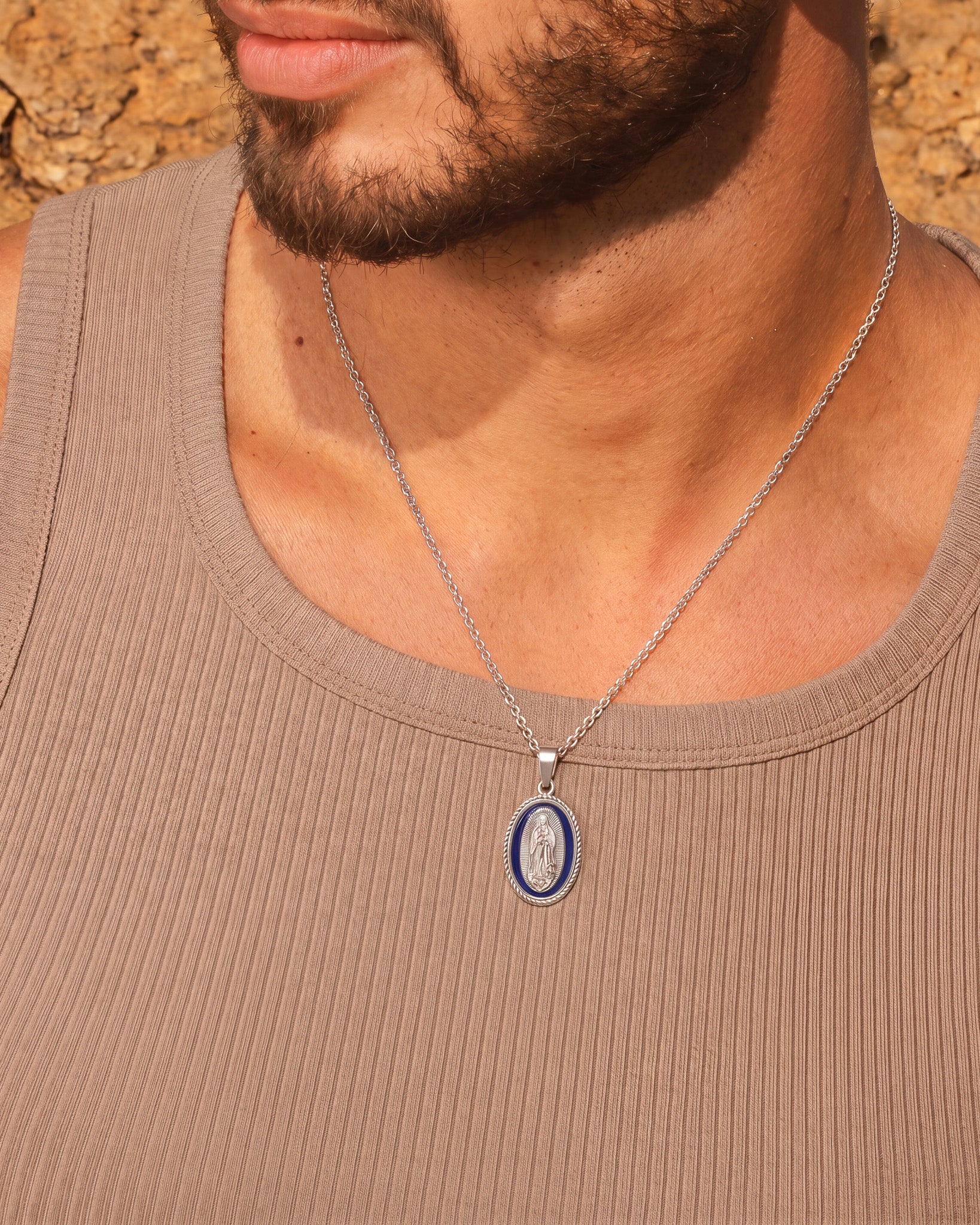 Man wearing a silver Virgin Mary pendant necklace with blue enamel oval medallion